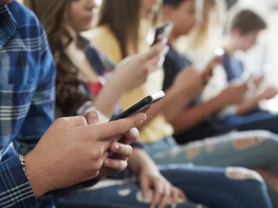 Close Up Of A Line Of High School Students Using Mobile Phones