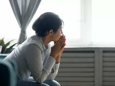 Pensive millennial Indian girl sit on couch at home look in distance thinking pondering, thoughtful young ethnic woman lost in thoughts feel stressed suffer from depression or emotional breakdown / Foto: Fizkes