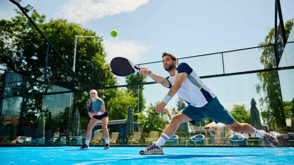 Young athlete playing padel in mixed doubles on outdoor court. Copy space. / Foto: Drazen Zigic
