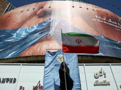 A woman holds an Iranian flag near an anti-U.S. billboard depicting U.S. President Donald Trump and the Strait of Hormuz, in Tehran, Iran, May 25, 2026. Majid Asgaripour/WANA (West Asia News Agency) via REUTERS ATTENTION EDITORS - THIS PICTURE WAS PROVIDED BY A THIRD PARTY