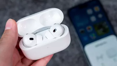 Jurmala, Latvia - 21 09 2023: In woman hand there is open case with headphones - AirPods Pro 2 generation. On background out of focus smartphone witch are connected to Air Pods.