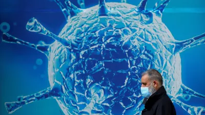 FILE PHOTO: A man wearing a protective face mask walks past an illustration of a virus outside a regional science centre, as the city and surrounding areas face local restrictions in an effort to avoid a local lockdown being forced upon the region, amid the coronavirus disease (COVID-19) outbreak, in Oldham, Britain August 3, 2020. REUTERS/Phil Noble/File Photo / Foto: Phil Noble