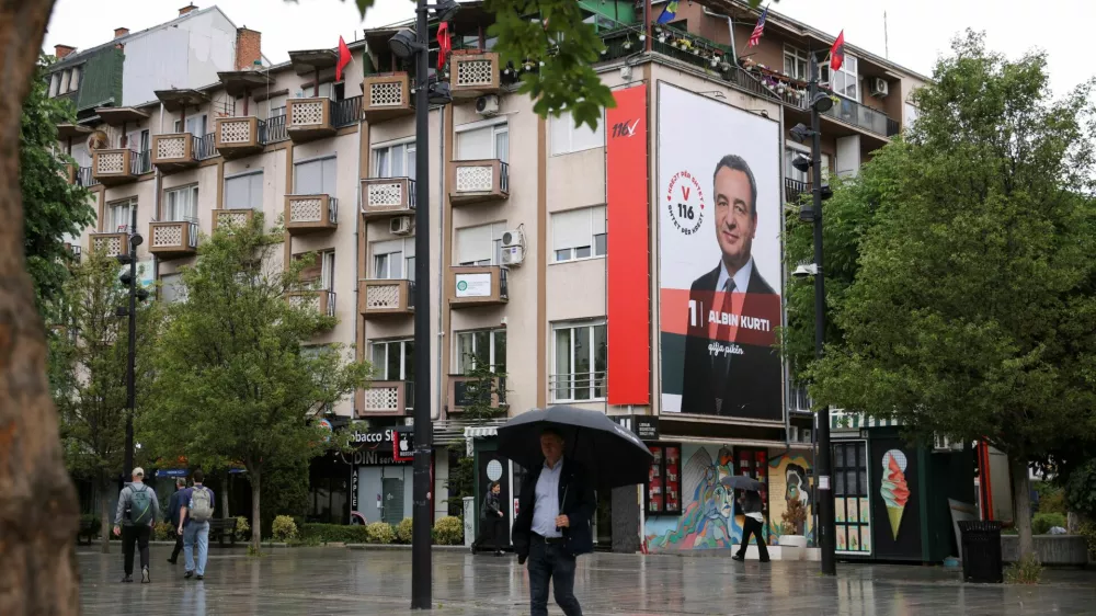 People walk near an election poster showing Prime Minister of Kosovo and Levizja Vetevendosje (Movement for Self-Determination) party leader Albin Kurti, in Pristina, Kosovo, June 4, 2026. Kosovo is to hold a snap parliamentary election, the third in just over a year, after parliament failed to elect a new head of state. REUTERS/Valdrin Xhemaj