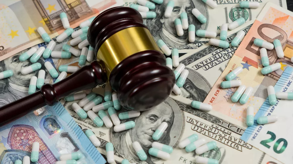 Wood judge's gavel and scattered colorful drugs on the dollar and euro cash background, drugs falsification, concept for medical negligence, bail. Overhead view.