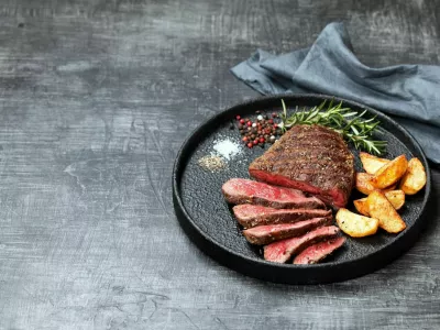 Sliced medium rare grilled beef steak and potato wedges, selective focus / Foto: Laperla_foto