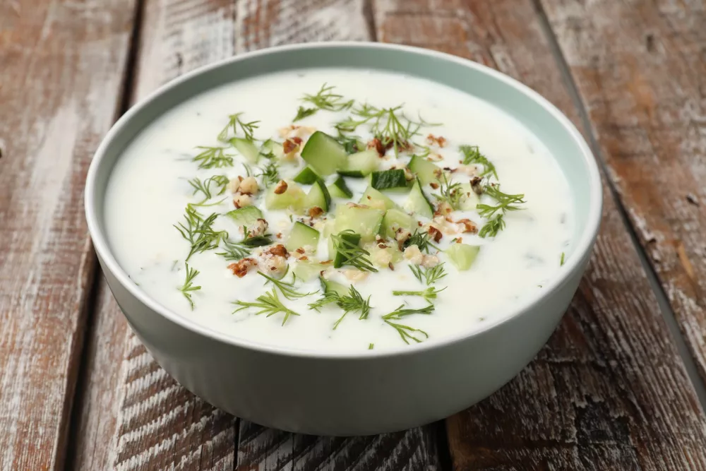 Tasty cucumber soup with dill and nuts in bowl on wooden table, closeup / Foto: Olga Yastremska