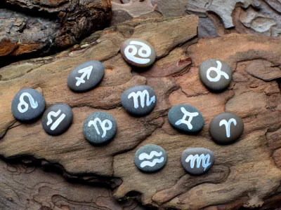 Zodiac symbols drawn on stones lie on a wooden table. Horoscope, fortune telling, predictions. / Foto: Oksana Lyskova Getty Images