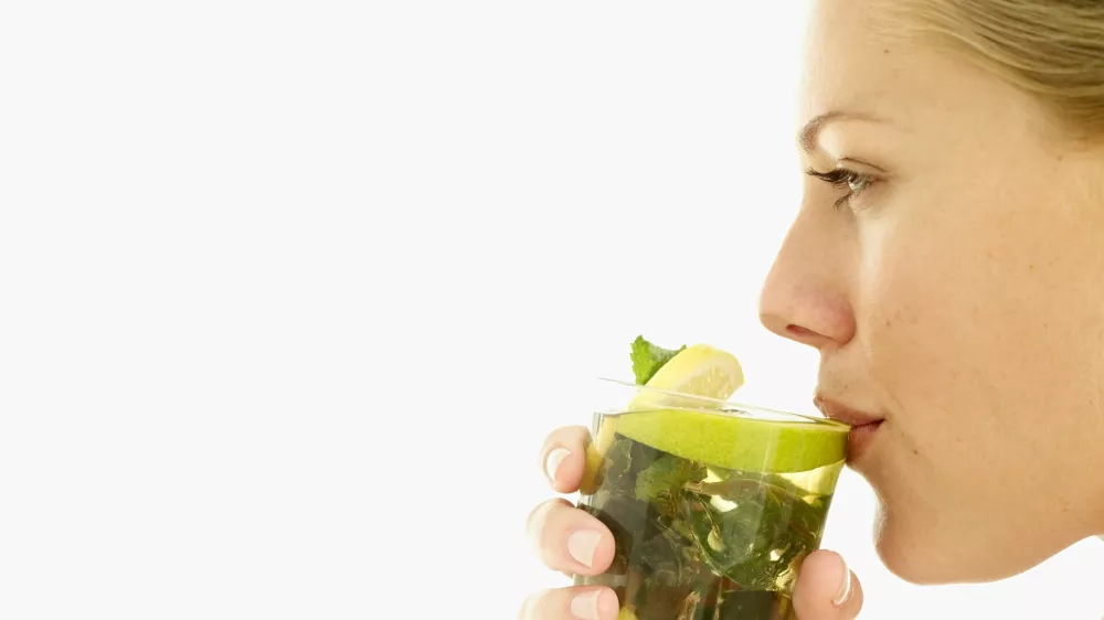 woman drinking a glass of lemon juice with mint leaves / Foto: Stockbyte