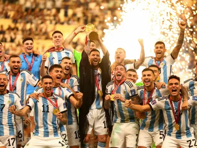 Soccer Football - FIFA World Cup Qatar 2022 - Final - Argentina v France - Lusail Stadium, Lusail, Qatar - December 18, 2022 Argentina's Lionel Messi lifts the World Cup trophy alongside teammates as they celebrate after winning the World Cup REUTERS/Kai Pfaffenbach