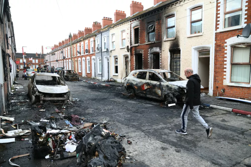 A man walks down a street after rioting broke out late Tuesday, in east Belfast, Northern Ireland, Wednesday, June 10, 2026, following a stabbing incident. (AP Photo/Peter Morrison)