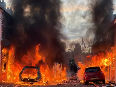 Vehicles set on fire by protesters burn on Lendrick Street in east Belfast, Northern Ireland, on Tuesday, June 9, 2026, after the arrest of a Sudanese man accused of stabbing a man in the northern part of the city. (PA via AP)