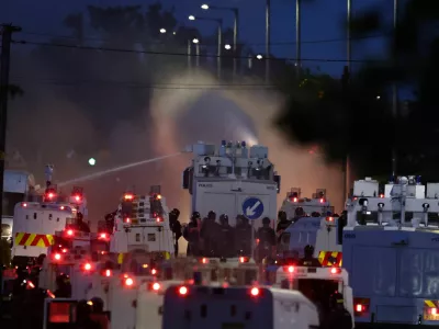 Police fire a water cannon towards rioters after they set fire to wheelie bins and removed a garden fence to use as a shield against the water cannon in Newtownabbey, Belfast, Northern Ireland, Wednesday June 10, 2026. (PA via AP)