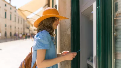 Beautiful girl taking the money from the ATM machine at her vacation.