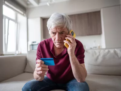 Naive elderly pensioner trusting sharing card number with scammers on phone. Identity theft, card fraud, manipulation, financial deception, personal data exposure, phone scam, dishonest schemes