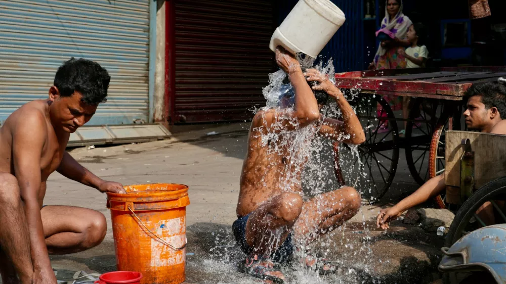 Indian rickshaw driver bathes from a roadside water tap during a hot summer day in Lucknow, northern Indian state of Utter Pradesh, Monday, June 15, 2026. (AP Photo/Rajesh Kumar Singh)