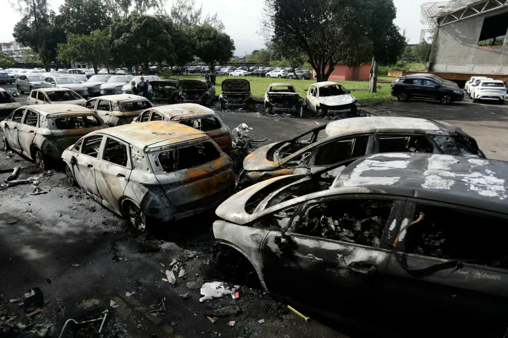 Burned vehicles fill a car dealership parking lot where, according to police, two helicopters collided in midair and crashed in Rio de Janeiro, Brazil, Sunday, June 14, 2026. (AP Photo/Bruna Prado)