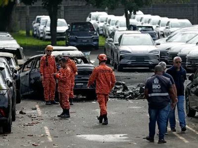 Emergency workers inspect the site where two helicopters reportedly collided in midair and crashed into a car dealership parking lot in Rio de Janeiro, Brazil, Sunday, June 14, 2026. (AP Photo/Bruna Prado)