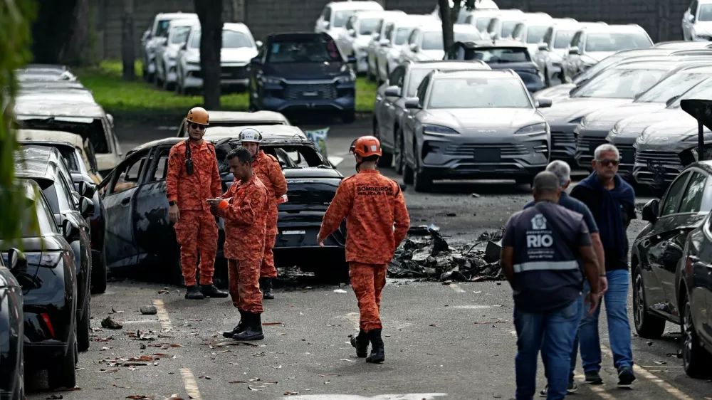 Emergency workers inspect the site where two helicopters reportedly collided in midair and crashed into a car dealership parking lot in Rio de Janeiro, Brazil, Sunday, June 14, 2026. (AP Photo/Bruna Prado)
