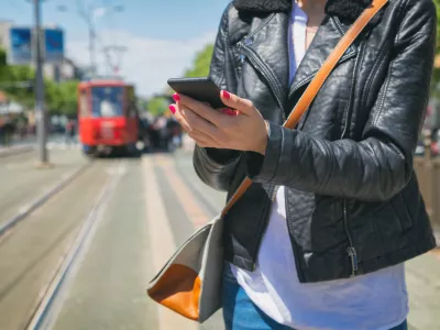 Using cellphone with defocused city tram.