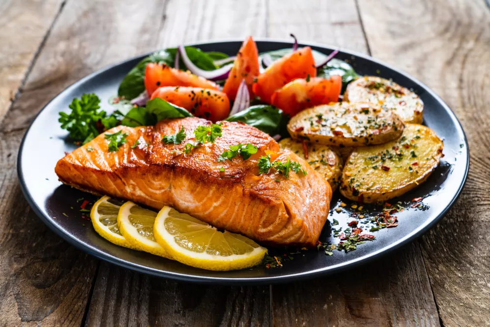 Barbecued salmon, fried potatoes and vegetables on wooden background / Foto: Gbh007