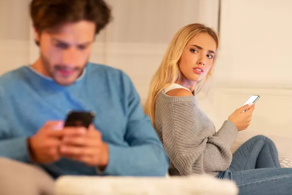 Infidelity. Wife Catching Cheating Husband Texting On Cellphone With Another Woman Sitting On Sofa At Home. Selective Focus / Foto: Prostock-studio Getty Images