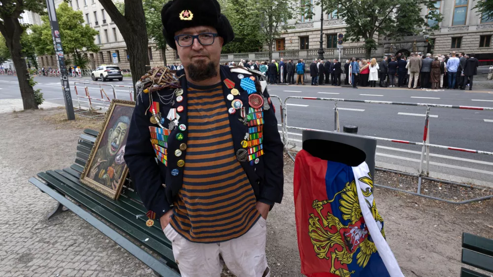 A man identified by Polish media as Robert Kuzovkov and by prosecutors as Robert K., in accordance with Polish privacy law, who they said was an artist who used the pseudonym Semyon Skrepetsky, poses for a photo with one of his paintings near the Russian Embassy in Berlin, Germany, on Friday, June 12, 2026, four days before Polish authorities said he was shot and killed in Biala Podlaska, Poland. (Vasily Krestyaninov/SOTA via AP)