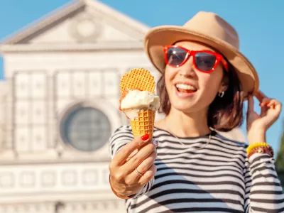 Young happy asian tourist woman eating ice-cream in front of the Croce basilica church in Florence