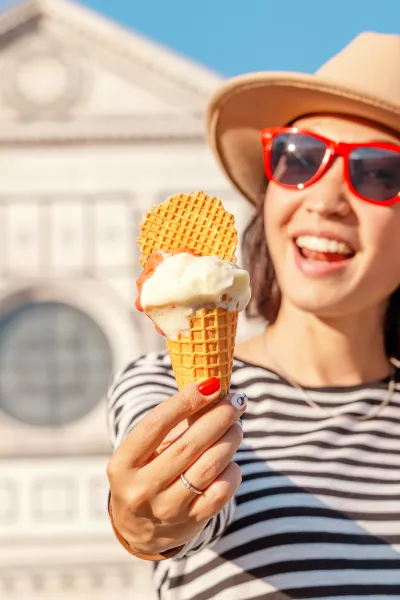 Young happy asian tourist woman eating ice-cream in front of the Croce basilica church in Florence