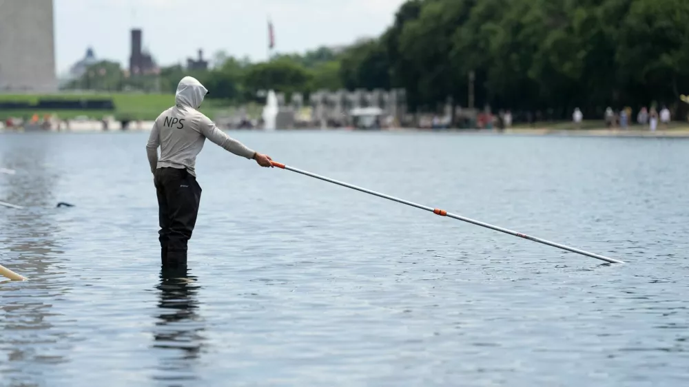 A worker vacuums algae from the Lincoln Memorial Reflecting Pool, after recent renovations following a directive from U.S. President Donald Trump to paint it blue ahead of the 250th anniversary of U.S. Independence, in Washington, D.C., U.S., June 21, 2026. REUTERS/Aaron Schwartz
