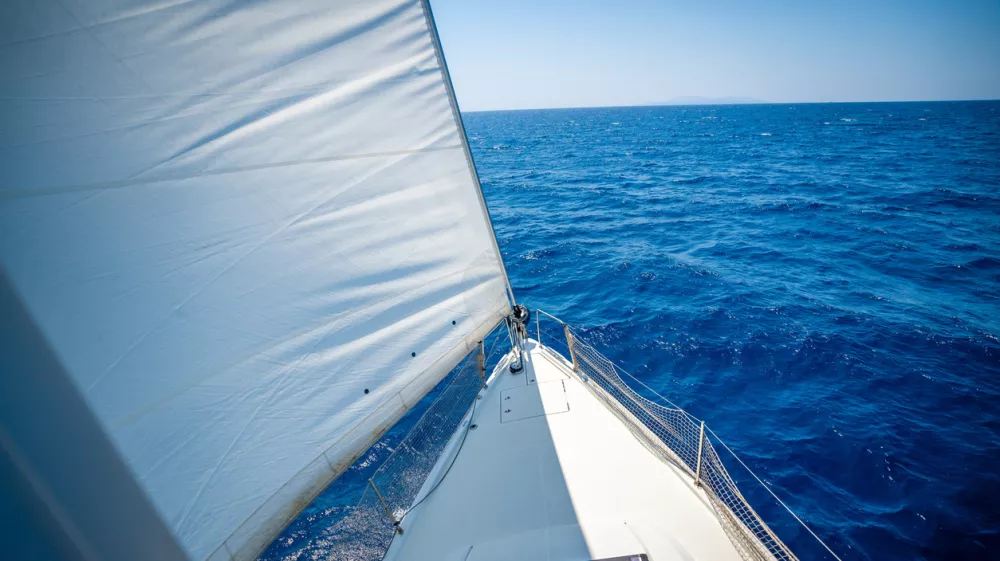 View from the mast down to the bow of a sailing yacht moving under full sails near Croatia. Freedom, adventure, yachting lifestyle and dynamic sea travel. High quality photo