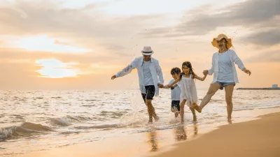 People of father, mother, children son and daughter family of four holding hands together walking outdoor, Happy family having fun running on a sandy beach at sunset, tropical summer travel vacations