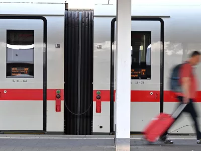 A passenger walks past an ICE train at Munich Central Station in Munich, Germany Wednesday, June 24, 2026, following the nationwide service disruption on the Deutsche Bahn network. (Peter Kneffel/dpa via AP)