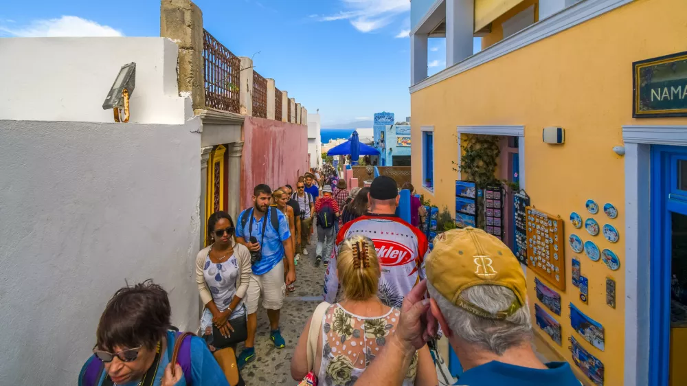 The effects of overtourism as tourists crowd the narrow streets through the Greek Isle resort of Oia and Fira on the island of Santorini, Greece. Santorini is one of the Cyclades islands in the Aegean Sea. It was devastated by a volcanic eruption in the 16th century BC, forever shaping its rugged landscape. The whitewashed, cubiform houses of its 2 principal towns, Fira and Oia, cling to cliffs above an underwater caldera crater. / Foto: Kirk Fisher