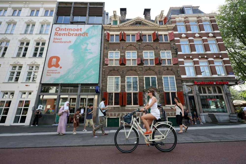 A woman rides a bike in front of the Rembrandt House Museum in Amsterdam, as the museum waves admission fees to offer a cool shelter during the heatwave hitting the country, while a code red alert is issued, in Amsterdam, the Netherlands, June 26, 2026. REUTERS/Nicolas Economou / Foto: Nicolas Economou