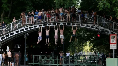 People hang from a bridge above the Canal Saint-Martin after public swimming was permitted in certain areas due to high temperatures amid a heatwave in Paris, France, June 26, 2026. REUTERS/Tom Nicholson   TPX IMAGES OF THE DAY / Foto: Tom Nicholson