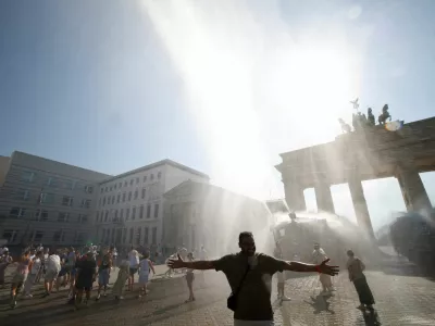 People enjoy the water sprayed by a police water cannon at the Brandenburg Gate during the ongoing heatwave in Berlin, Germany, June 27, 2026. REUTERS/Axel Schmidt