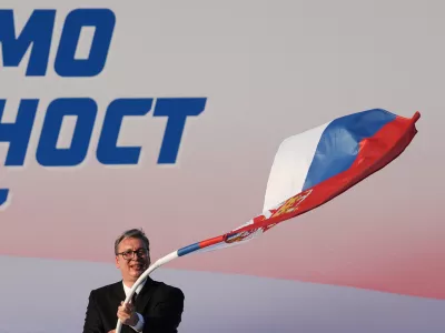 Serbian President Aleksandar Vucic waves a Serbian flag during a rally of the ruling Serbian Progressive Party (SNS) in Belgrade, Serbia, Saturday, June 27, 2026, where he announced that he will resign in the coming weeks. (AP Photo/Darko Vojinovic)