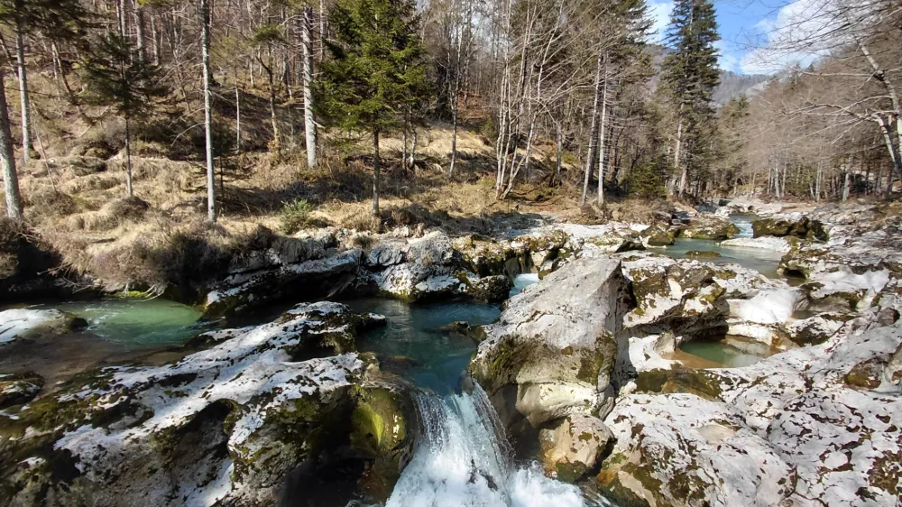 Pot obiskovalca popelje skozi ozko sotesko, ob kristalno čisti reki Mostnici. 