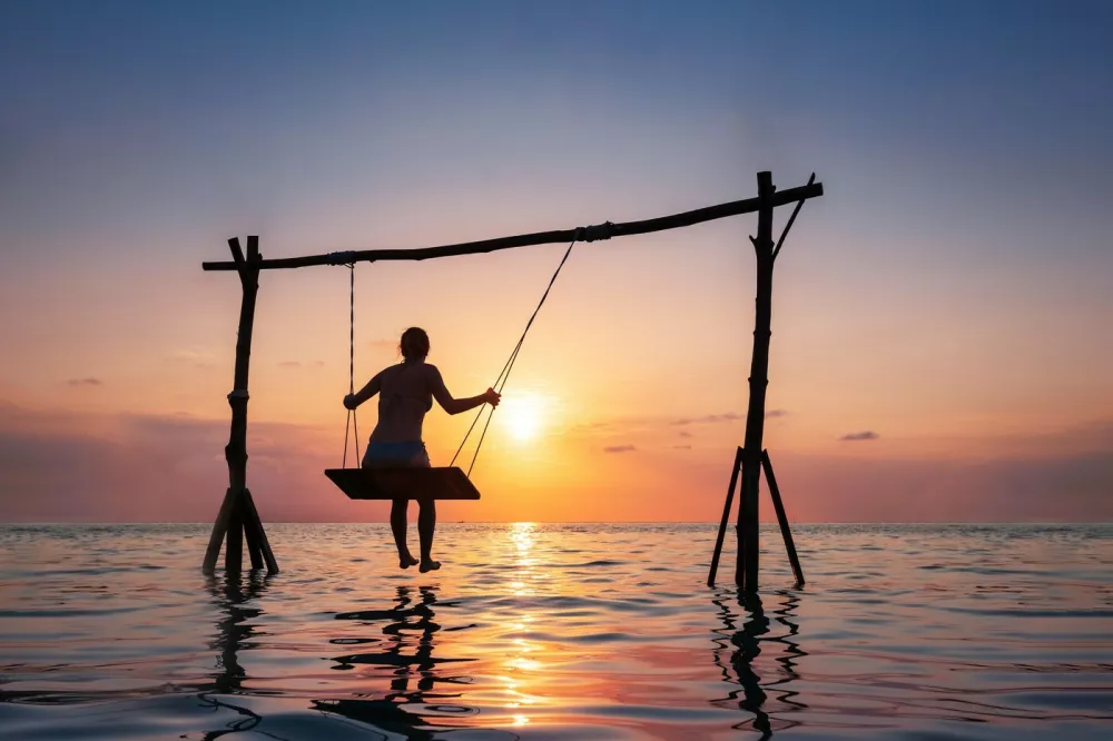 2A9CJXY Happy girl relaxing at the beach on rope swing above sea water at sunset, summer vacation holidays resort,Image: 636976045, License: Rights-managed, Restrictions: View your order summary at: https://www.alamy.com/Order-summary.asp?OrderID={B86A448A-6A74-4901-B385-D1249D50756E} Your Ref: DY56389434 Downloaded: 24 June 2021 Image ID: 2A9CJXY, Model Release: no 
