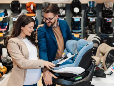 Beautiful couple choosing and buying car safety seat for their baby. Parenthood and child expecting concept.