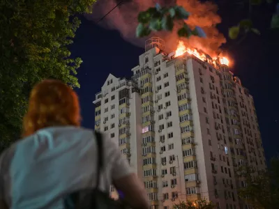 A woman looks at an apartment building burning after a Russian missile attack in Kyiv, Ukraine, Thursday, July 2, 2026. (AP Photo/Danylo Antoniuk)