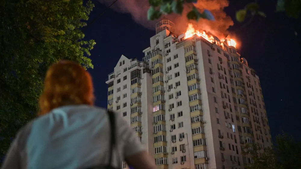 A woman looks at an apartment building burning after a Russian missile attack in Kyiv, Ukraine, Thursday, July 2, 2026. (AP Photo/Danylo Antoniuk)