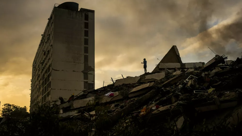 A man stands atop a mountain of rubble three days after twin earthquakes struck, in La Guaira, Venezuela, Saturday, June 27, 2026. (AP Photo/Matias Delacroix)