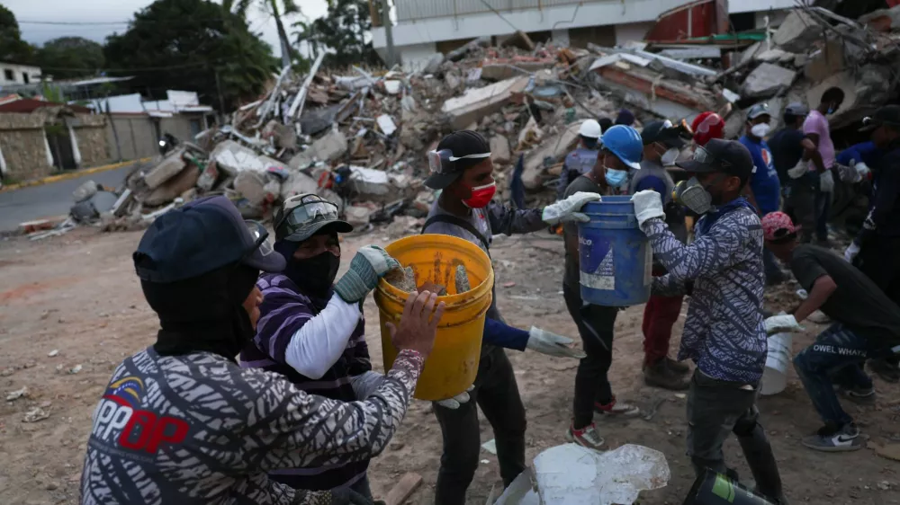Rescuers pass rubble in buckets as they search through debris in the aftermath of the June 24 earthquakes, in La Guaira, Venezuela, July 4, 2026. REUTERS/Pablo Sanhueza