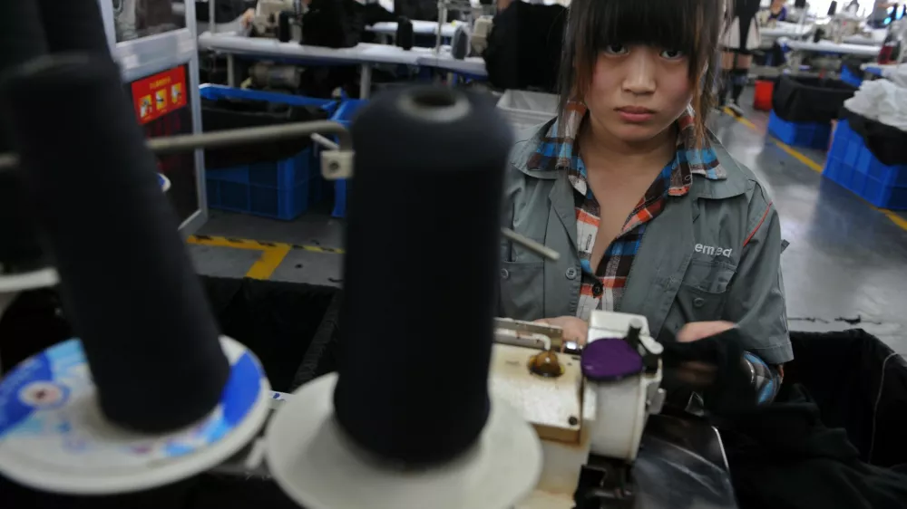 A college student looks up as she works at a garment factory in Jiaxing, Zhejiang province, October 19, 2012. More and more factories in China move inland from higher-cost coastal manufacturing centers, labor is turning out to be neither as cheap nor abundant as many companies believed. As a result, many multinationals and their suppliers are corralling millions of teenage vocational students to work long hours doing assembly line jobs that might otherwise go unfilled - jobs that the students have no choice but to accept. Picture taken October 19, 2012. REUTERS/Stringer (CHINA - Tags: BUSINESS) CHINA OUT. NO COMMERCIAL OR EDITORIAL SALES IN CHINA