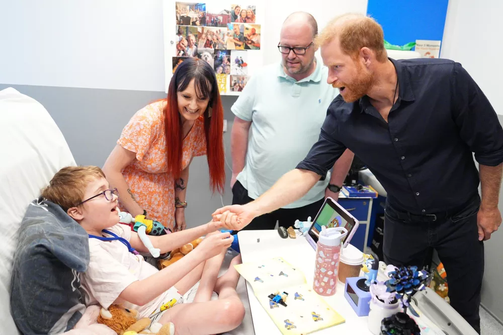 Britain's Prince Harry, patron of WellChild, meeting patient Alec Hill, who has a rare chromosomal condition and a rare immune system disease, and is in a wheelchair as a result of brain damage, with his mother Kelly Hill and father Stuart Hill, during a visit to the Birmingham Children's Hospital to celebrate the 20th anniversary of the very first WellChild Nurse, in Birmingham, England, Thursday July 9, 2026. (Aaron Chown/Pool Photo via AP)