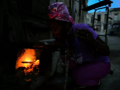 Odalys Ramos, 62, lights firewood to prepare coffee in front of her home as Cuba's national electric grid collapsed at midday, leaving around 10 million people without power, in Havana, Cuba, July 6, 2026. REUTERS/Norlys Perez