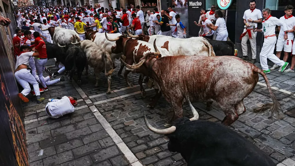 Revelers run alongside Fuente Ymbro's fighting bulls during the first running of the bulls at the San Ferm&iacute;n festival in Pamplona, Spain, Tuesday, July 7, 2026. (AP Photo/Miguel Oses)