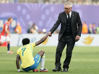 Brazil head coach Carlo Ancelotti helps Brazil's Vinicius Junior (7) get upduring the World Cup round of 16 soccer match between Brazil and Norway in East Rutherford, N.J., near New York, Sunday, July 5, 2026. (AP Photo/Adam Hunger)