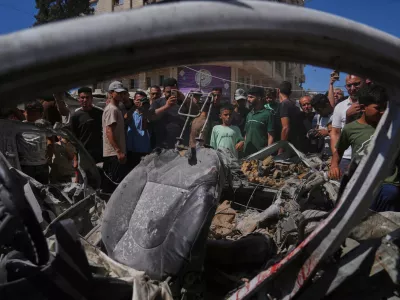Palestinians gather around a car hit in an Israeli military strike that, according to health authorities, killed at least one person in Gaza City, Thursday, July 9, 2026. (AP Photo/Jehad Alshrafi)